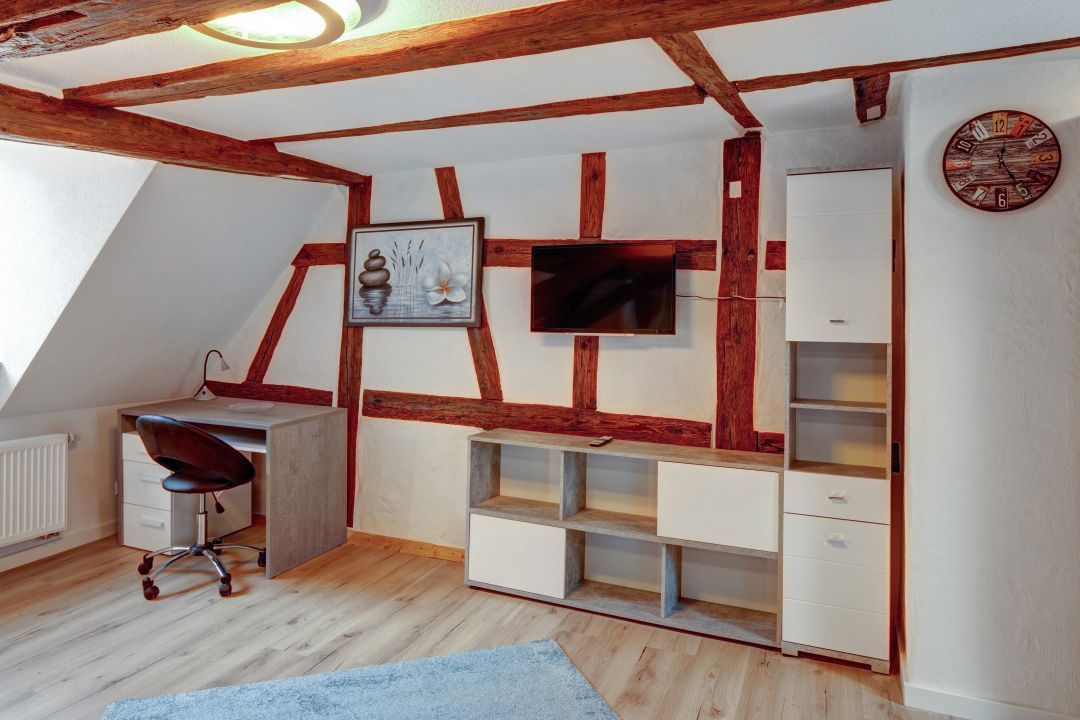 Dachwohnung mit sichtbarem Fachwerk, Schreibtisch und Wohnwand